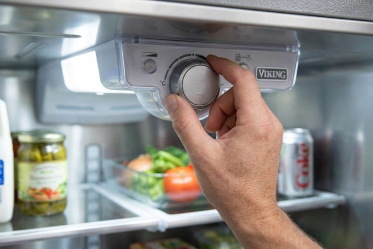 Hand adjusting the temperature control dial inside a Viking refrigerator